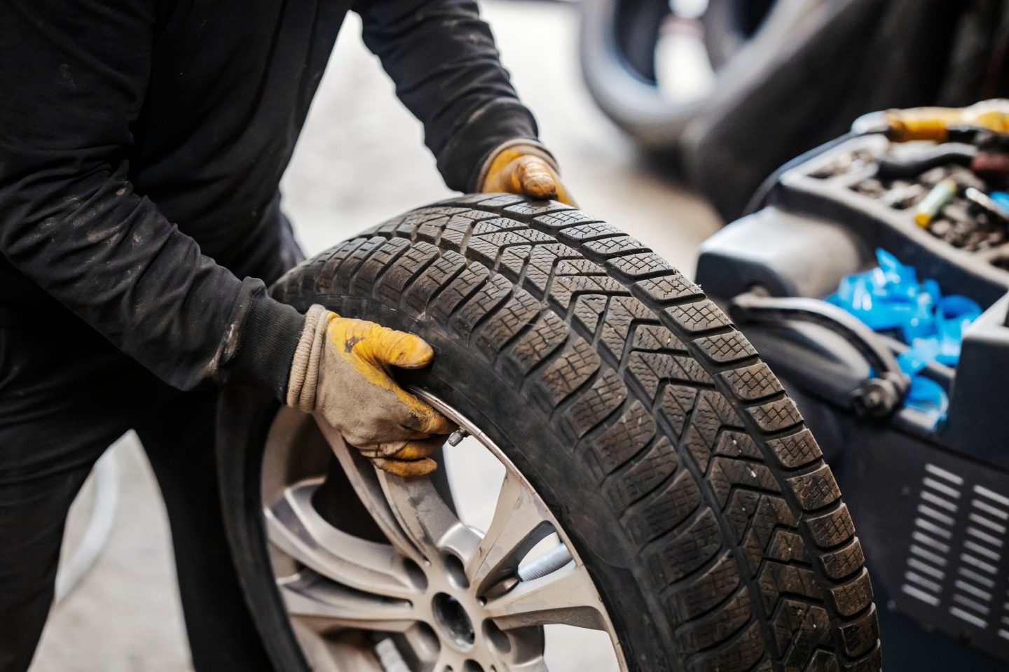 Cropped,Picture,Of,Mechanic,Holding,Car,Wheel,At,Vulcanizing,Workshop.