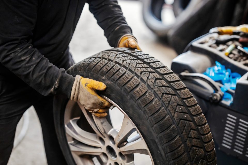 Cropped,Picture,Of,Mechanic,Holding,Car,Wheel,At,Vulcanizing,Workshop.